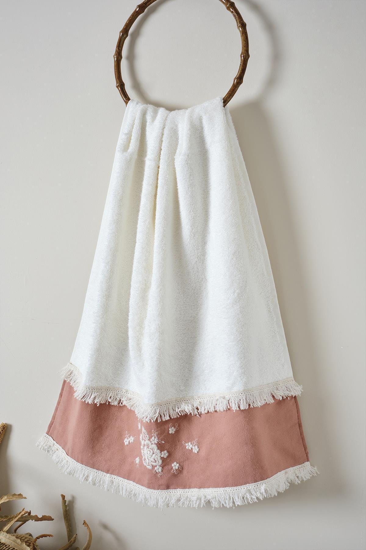 White, pink lace-embroidered and tasseled bath towel, hanging on a hook