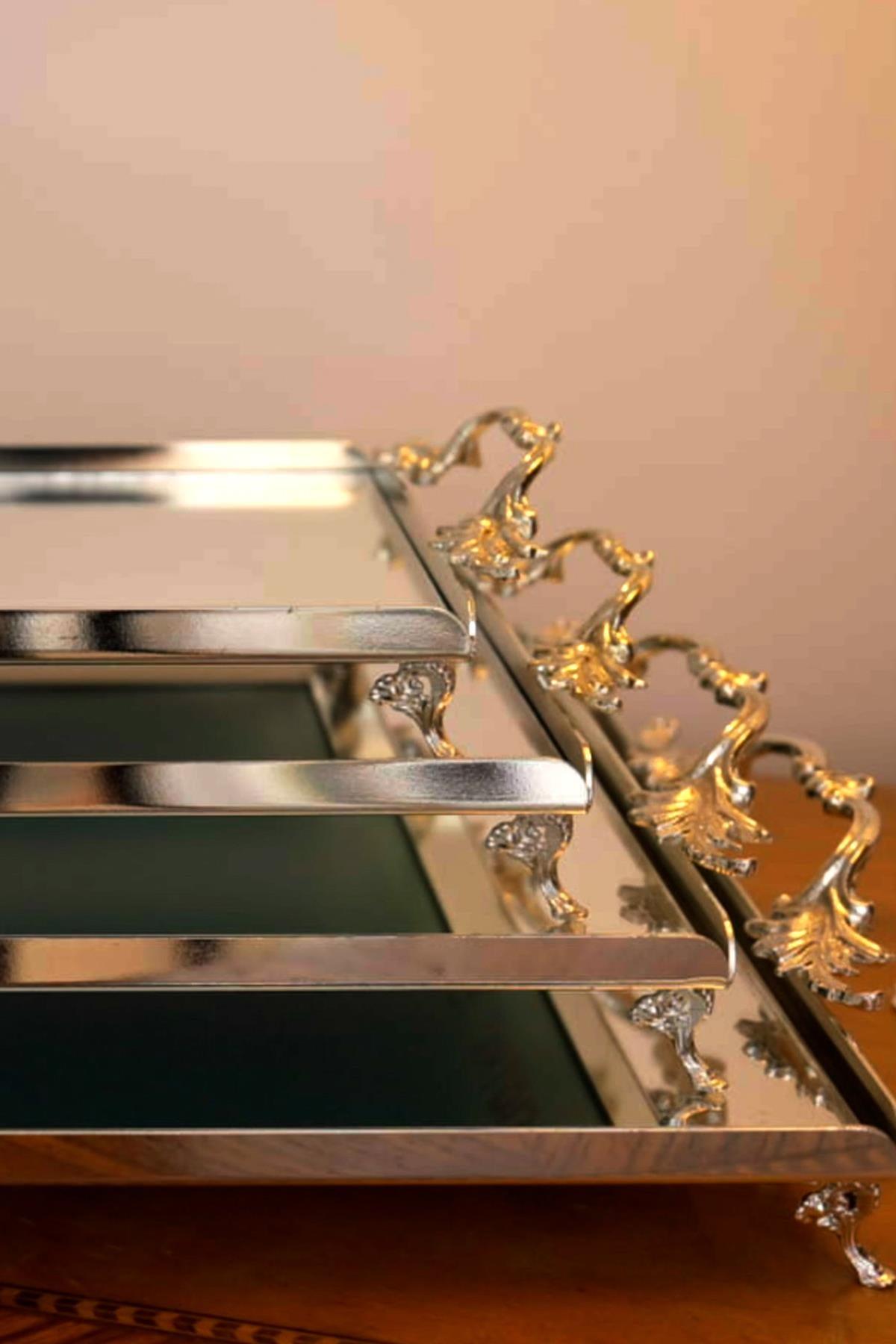 Large silver-colored serving trays with elegant handles, featuring a decorative footed base and a glamorous design.