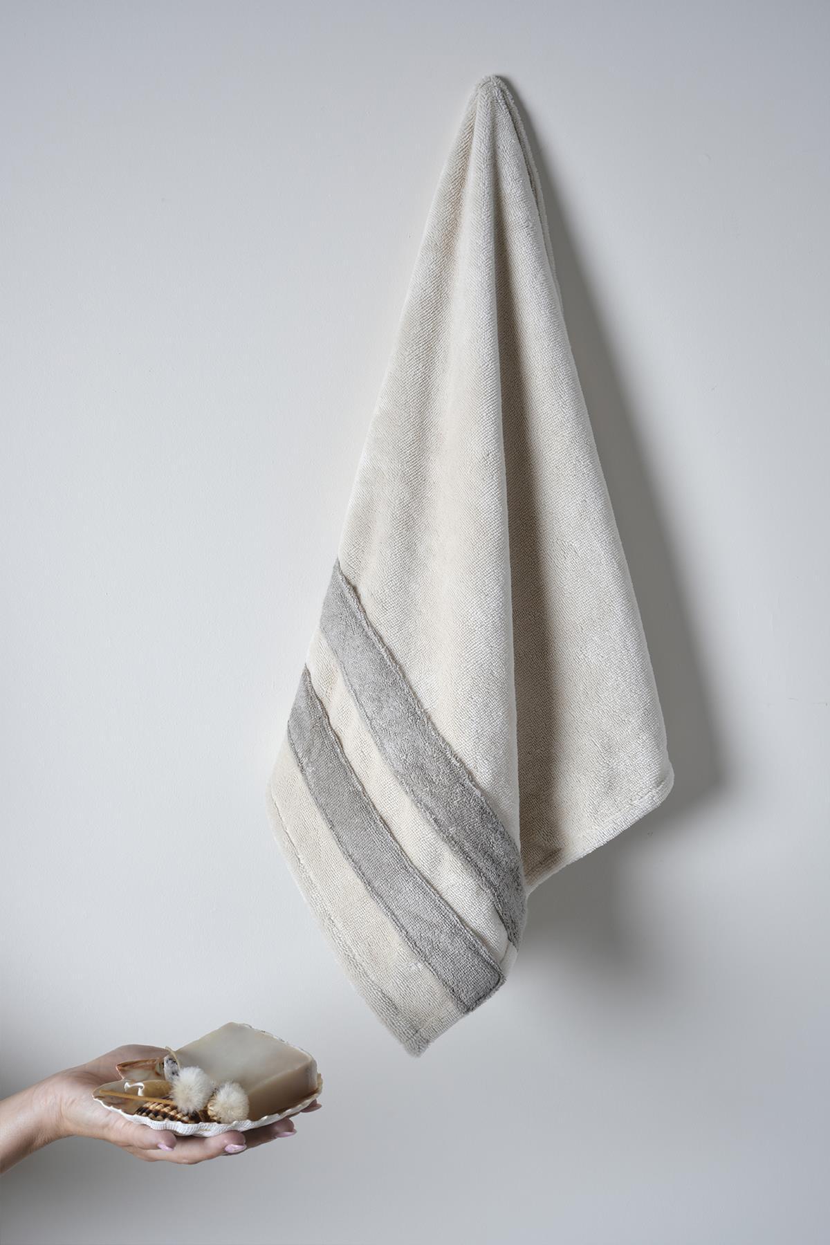 Beige cotton bathrobe hanging on the wall, with hand soap and bathroom accessories.