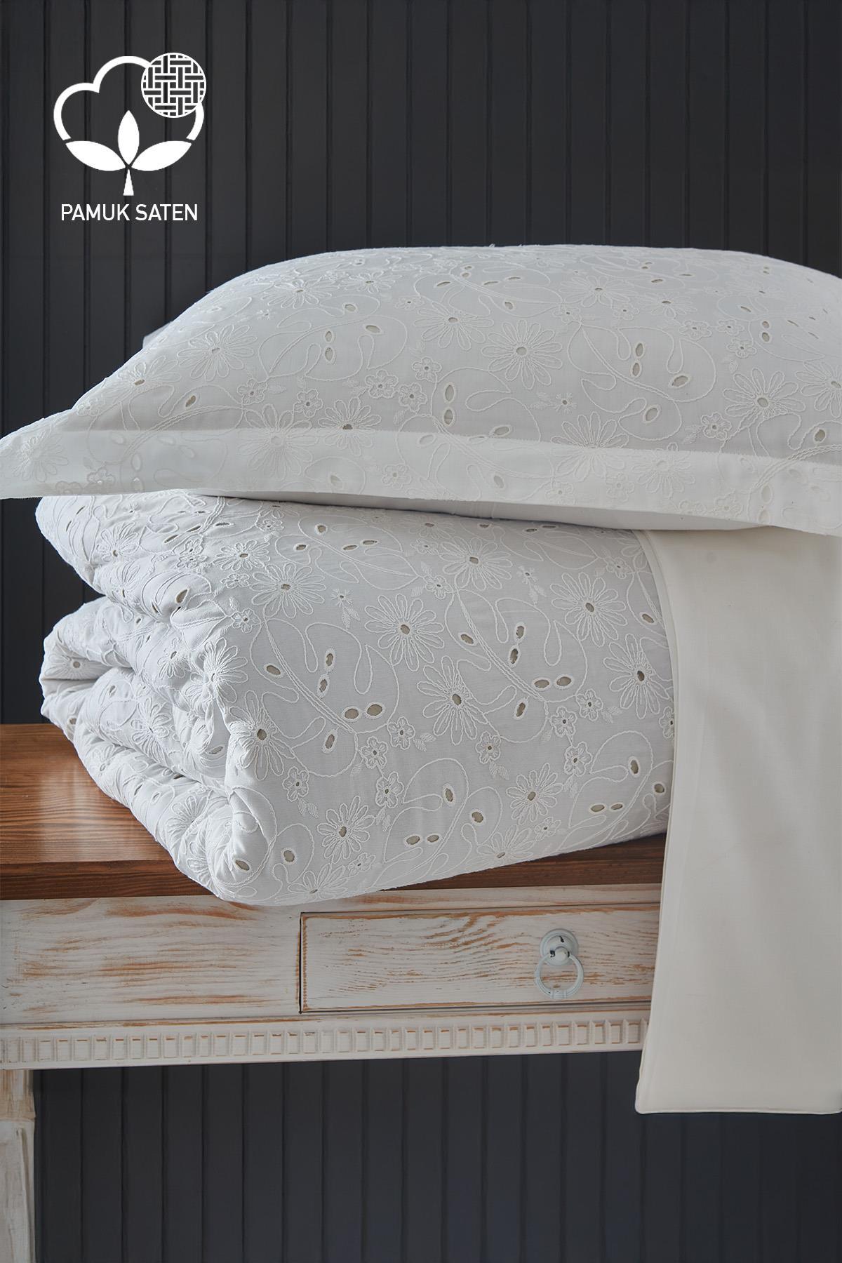 White embroidered cotton sateen double duvet cover set, folded on a table.