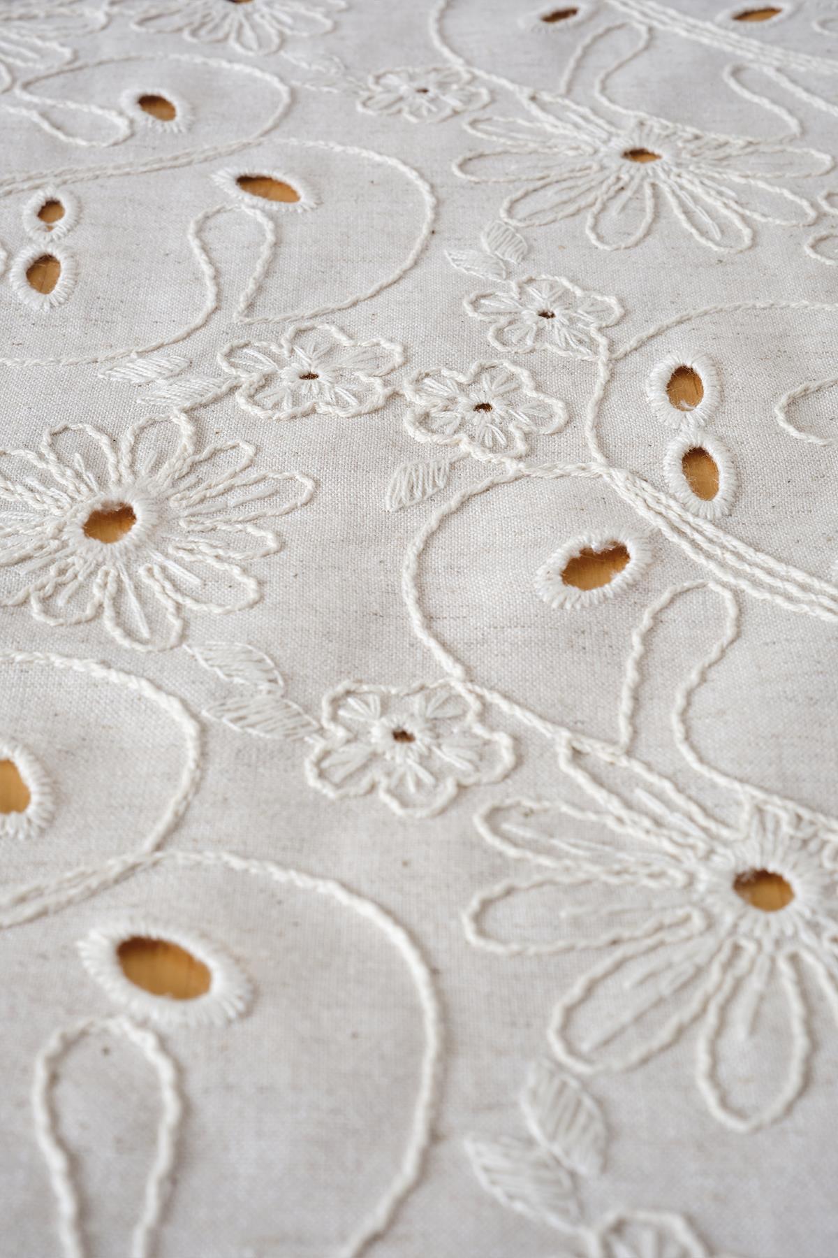 Detailed view of a cream-colored, floral-patterned cotton woven table runner