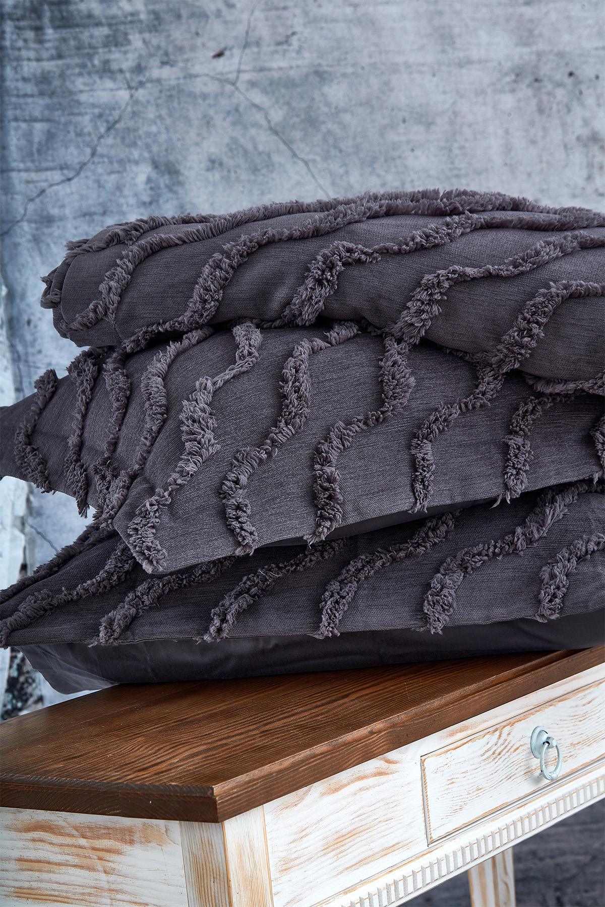 Dark gray, linen-textured, tassel-detailed single bedspread on a rustic background.