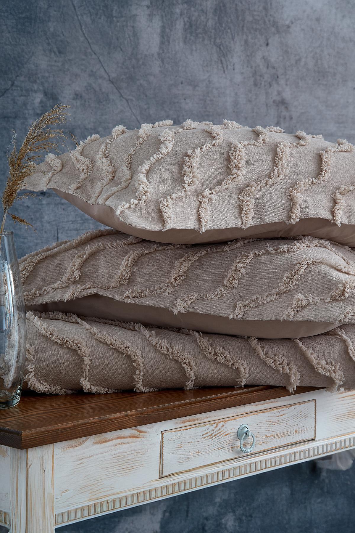 Linen-textured, beige, wavy-patterned single bedspread and decorative pillows