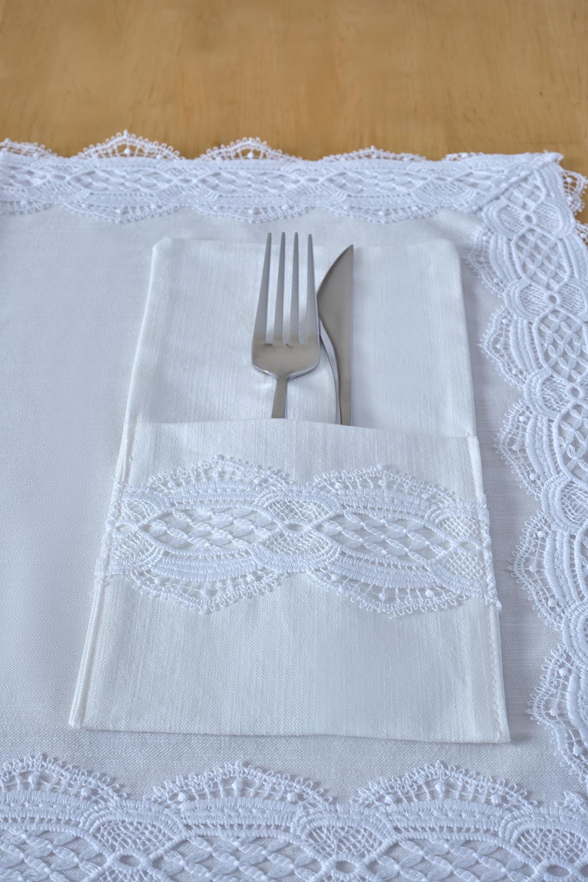 White lace-embroidered fabric napkin holder with fork and knife on the table