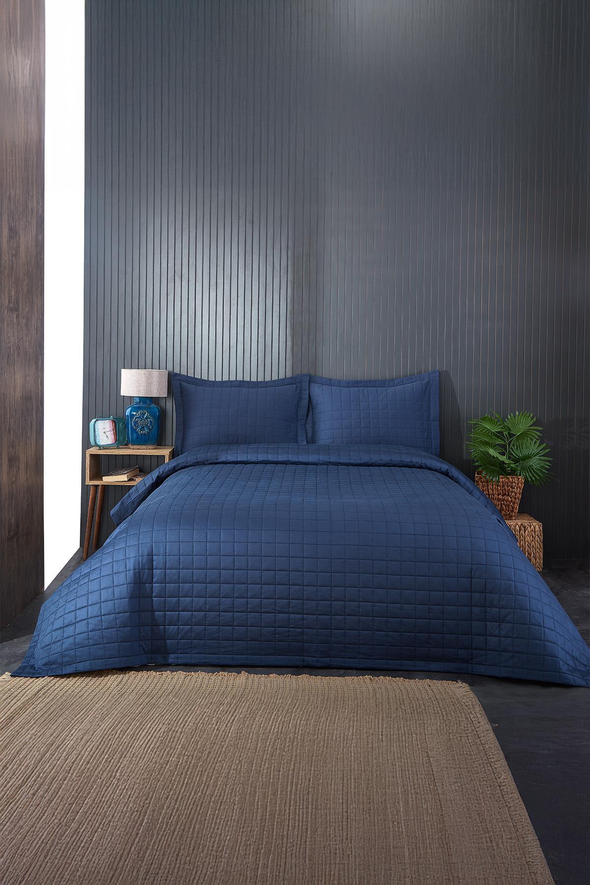 Navy blue quilted double bedspread and pillowcase set in a modern bedroom
