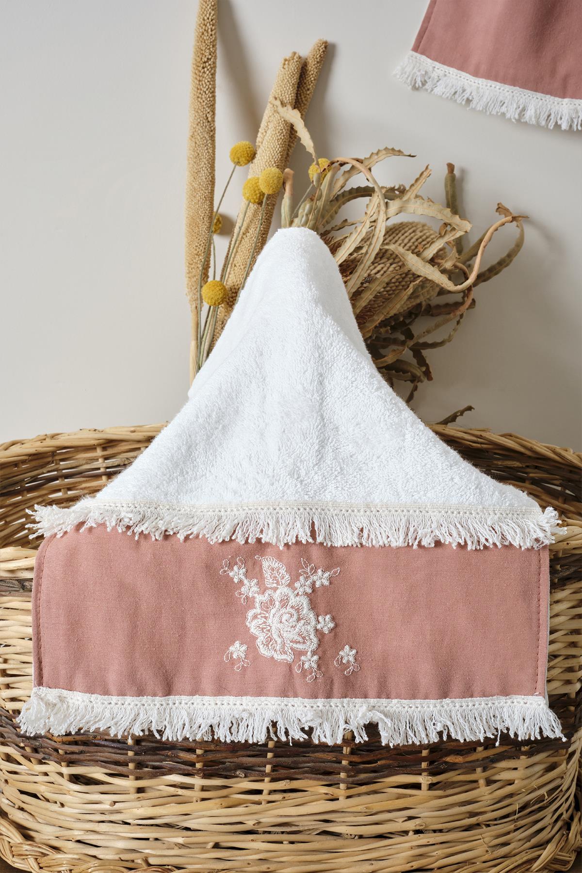 Small pink lace towel with embroidered edges, displayed decoratively on a basket.