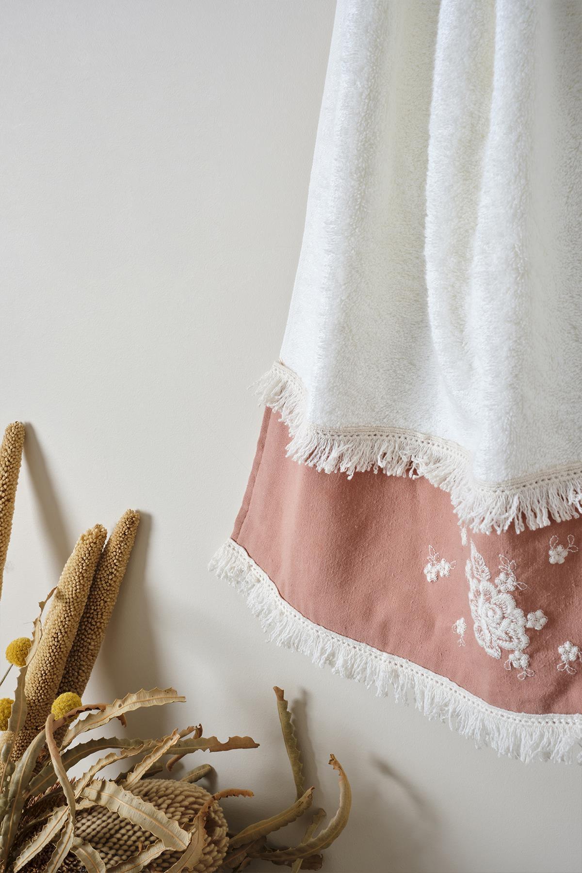 Decorative towel with burgundy embroidery and tasseled edges, 50x90 cm, hanging in a natural setting
