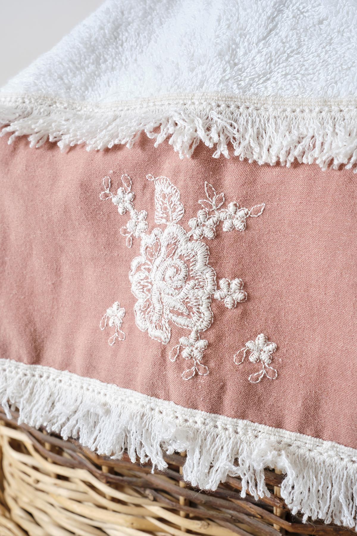 Close-up of a pink and white bath towel with lace embroidery and tassels