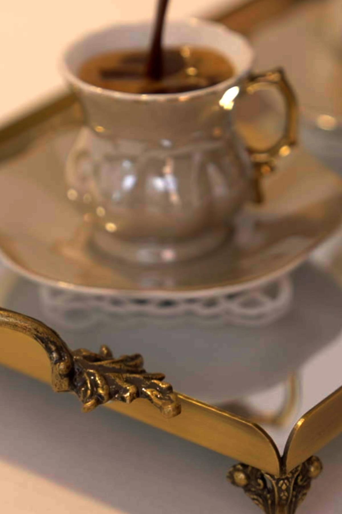 Coffee served in a porcelain cup on a mini tray with antique gold-colored handles
