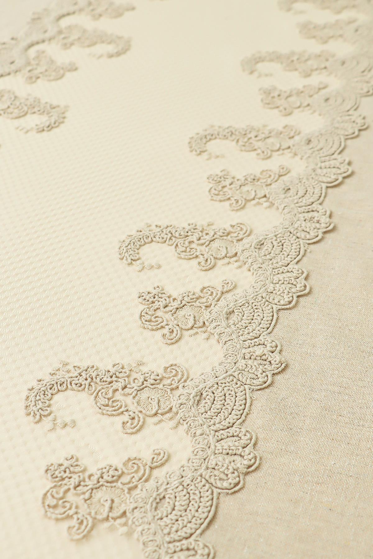 Cream-colored lace-detailed tablecloth with elegant patterns and textured fabric.